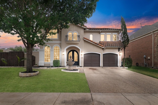 mediterranean / spanish-style house with a garage, a yard, and a balcony