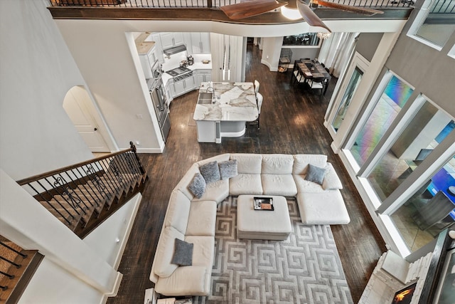 living room featuring a fireplace, sink, dark wood-type flooring, and a high ceiling