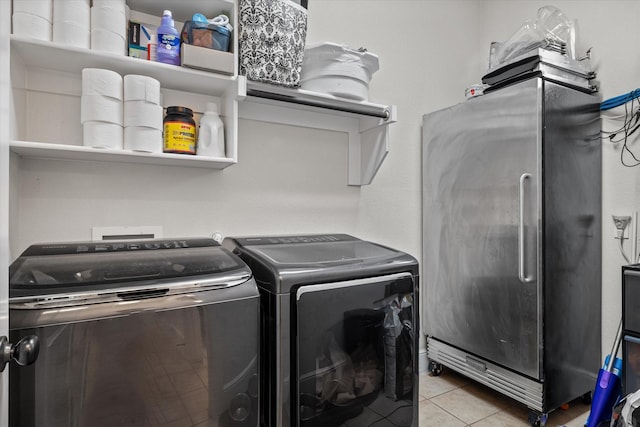 laundry area with light tile patterned floors and washing machine and clothes dryer