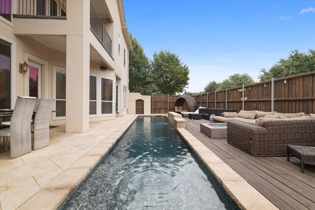 view of pool featuring a deck and an outdoor living space with a fire pit