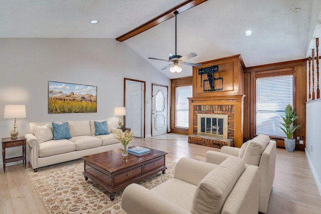 living room with a fireplace, lofted ceiling with beams, light hardwood / wood-style floors, and ceiling fan