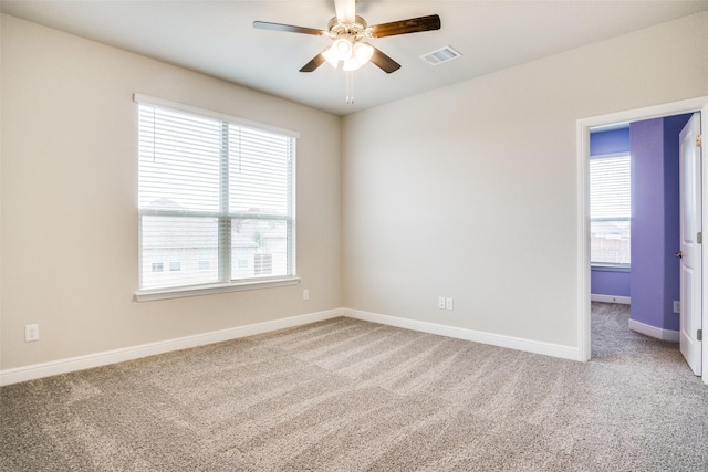 spare room featuring a wealth of natural light, ceiling fan, and carpet