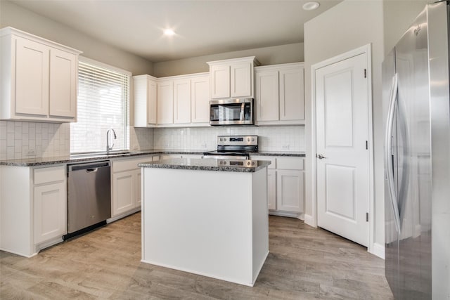 kitchen with white cabinets, a center island, light wood-type flooring, and appliances with stainless steel finishes