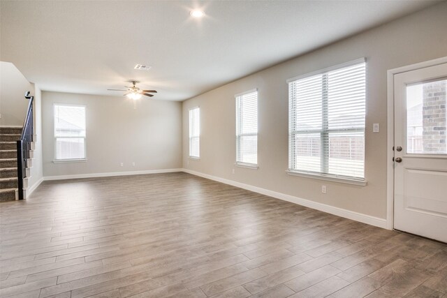 unfurnished living room with a wealth of natural light, ceiling fan, and hardwood / wood-style flooring