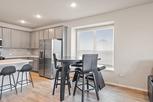 kitchen with light hardwood / wood-style flooring, decorative backsplash, stainless steel fridge, and gray cabinets