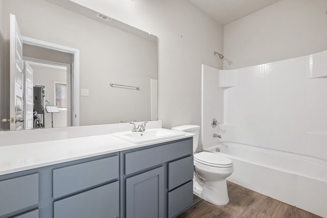 full bathroom with hardwood / wood-style flooring, vanity, tub / shower combination, and toilet