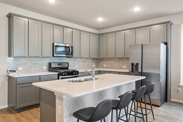 kitchen featuring gray cabinets, a kitchen island with sink, sink, and stainless steel appliances