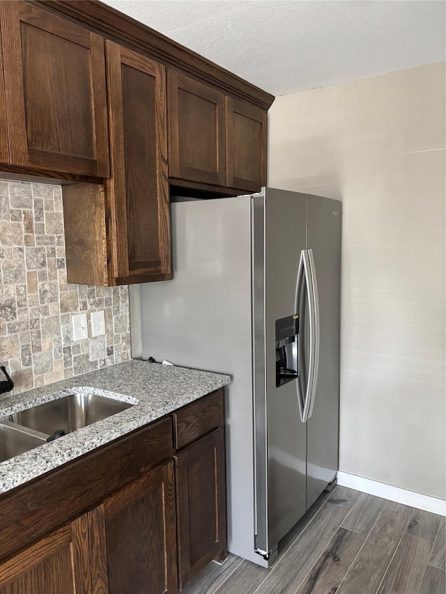 kitchen with light stone countertops, stainless steel fridge with ice dispenser, and dark brown cabinetry