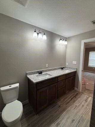 bathroom with hardwood / wood-style flooring, toilet, and vanity