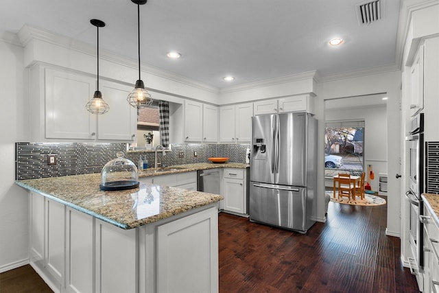 kitchen featuring dark wood-type flooring, white cabinetry, stainless steel appliances, decorative light fixtures, and kitchen peninsula