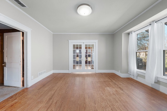 empty room with french doors, light wood-type flooring, and crown molding