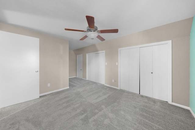 unfurnished bedroom featuring multiple closets, ceiling fan, and carpet