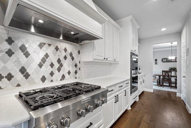 kitchen with wall chimney range hood, backsplash, stainless steel appliances, dark hardwood / wood-style floors, and white cabinets