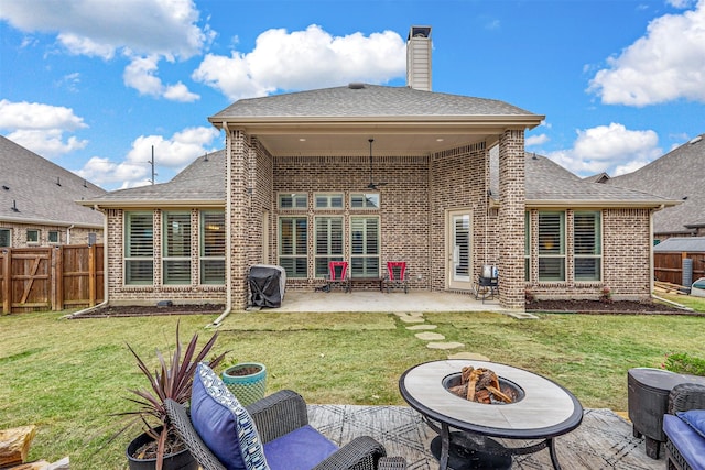 rear view of property featuring a patio, a lawn, and an outdoor fire pit