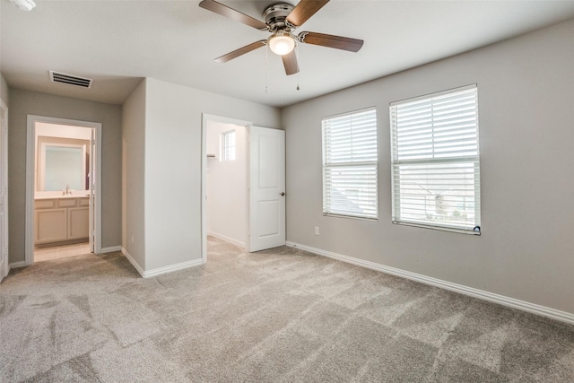 unfurnished bedroom featuring ceiling fan, sink, light carpet, and ensuite bath