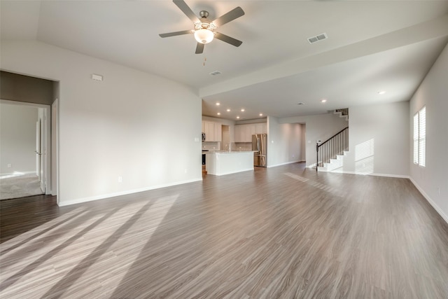 unfurnished living room featuring ceiling fan, hardwood / wood-style floors, vaulted ceiling, and sink