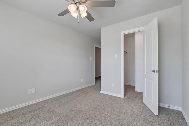 unfurnished bedroom with a walk in closet, ceiling fan, and light colored carpet