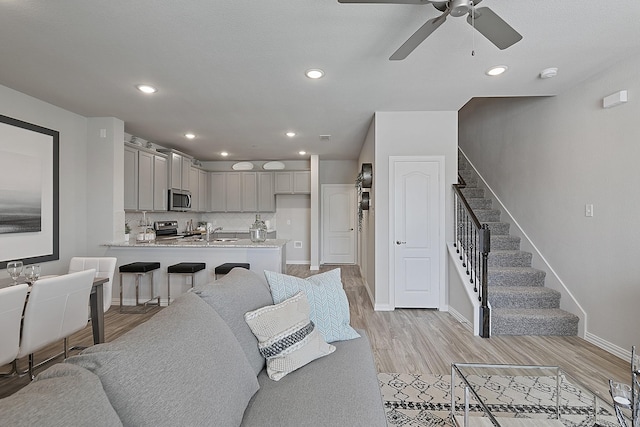 living room with ceiling fan, light wood-type flooring, and sink