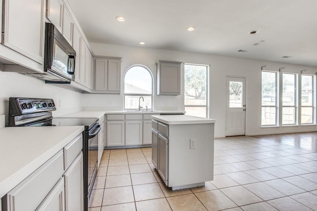 kitchen featuring gray cabinetry, a center island, black appliances, sink, and light tile patterned flooring