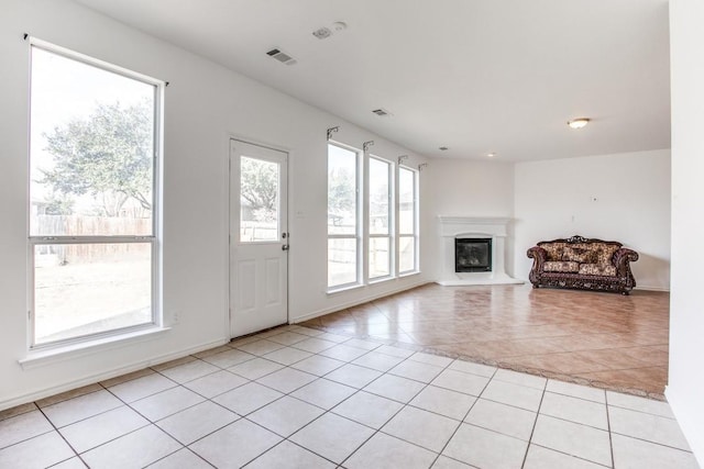 unfurnished living room with light tile patterned floors and a wealth of natural light