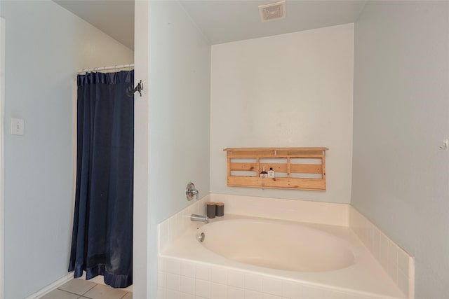 bathroom with a relaxing tiled tub and tile patterned flooring