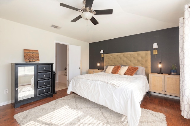 bedroom featuring lofted ceiling, dark hardwood / wood-style floors, ceiling fan, and ensuite bath