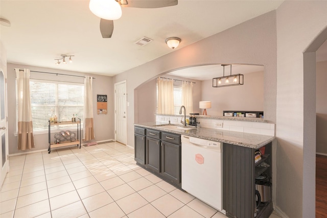 kitchen featuring sink, hanging light fixtures, plenty of natural light, white dishwasher, and light stone countertops