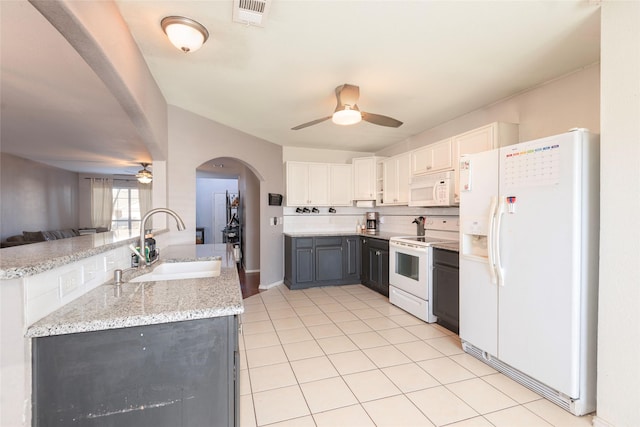 kitchen with sink, white appliances, white cabinetry, backsplash, and light stone countertops