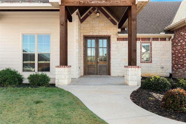 view of exterior entry with a yard and french doors