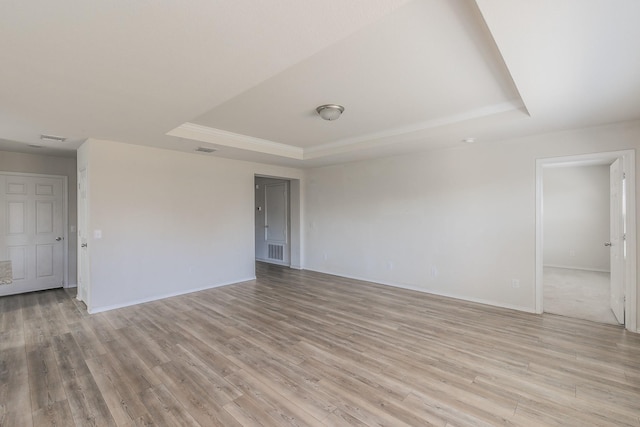 unfurnished room featuring a raised ceiling and light wood-type flooring