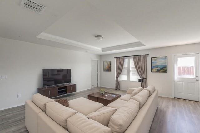 living room with hardwood / wood-style flooring and a tray ceiling