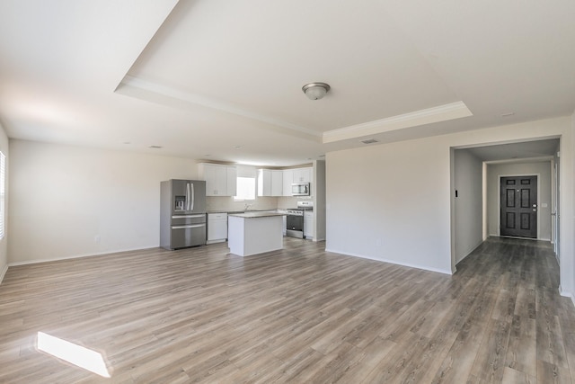 unfurnished living room with hardwood / wood-style flooring, sink, and a tray ceiling