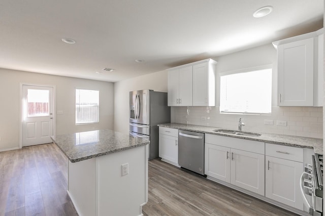 kitchen featuring stainless steel appliances, sink, a kitchen island, and white cabinets