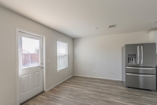 interior space featuring light wood-type flooring and stainless steel fridge with ice dispenser