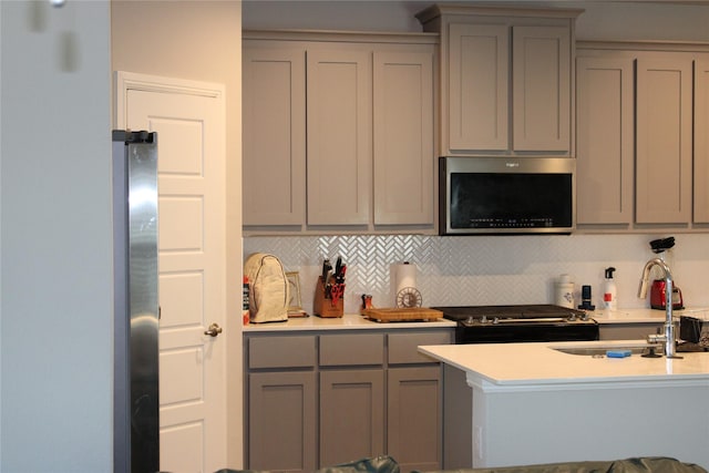 kitchen featuring backsplash, stainless steel appliances, gray cabinetry, and sink