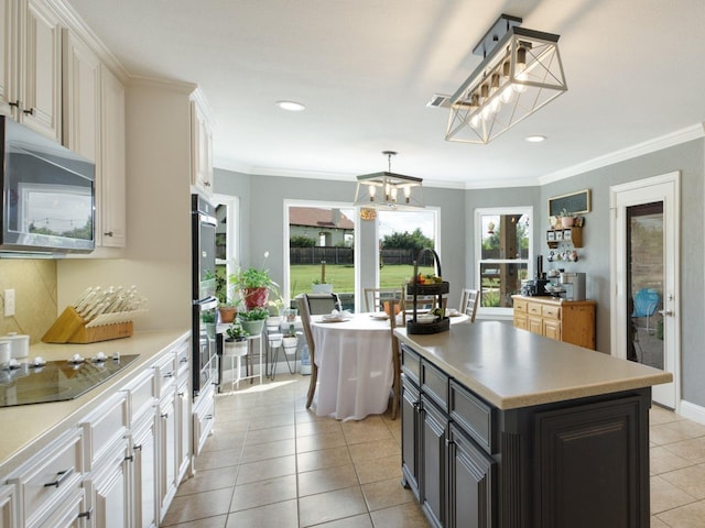 kitchen featuring a center island, an inviting chandelier, white cabinets, hanging light fixtures, and black electric cooktop