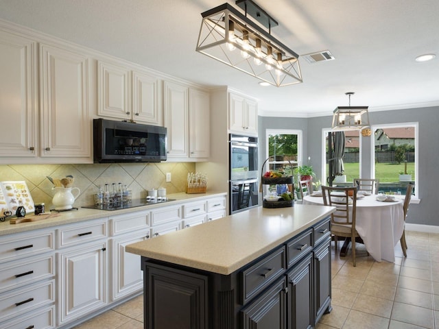 kitchen featuring crown molding, hanging light fixtures, light tile patterned floors, appliances with stainless steel finishes, and a kitchen island