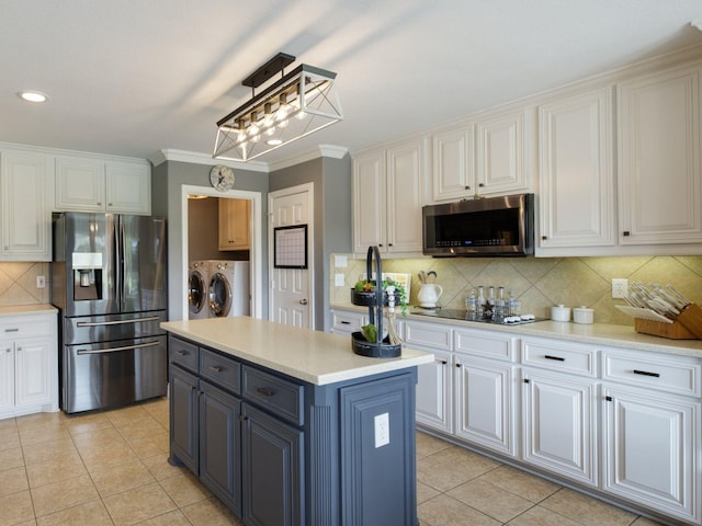 kitchen with a kitchen island, washing machine and dryer, white cabinetry, and appliances with stainless steel finishes