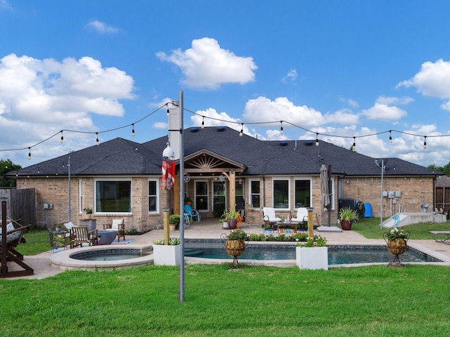 rear view of property featuring a lawn, a patio area, and an in ground hot tub