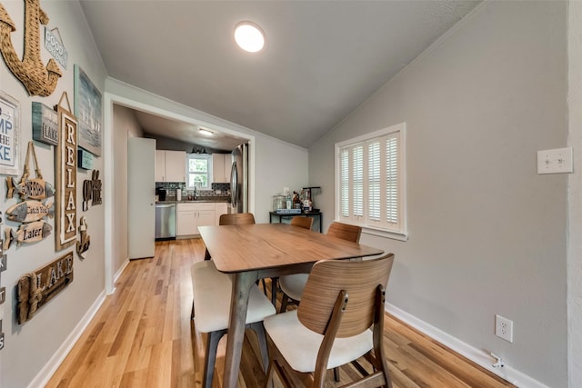 dining room with sink, light hardwood / wood-style floors, and lofted ceiling