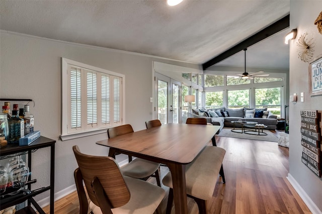 dining area with wood-type flooring, plenty of natural light, vaulted ceiling with beams, and french doors