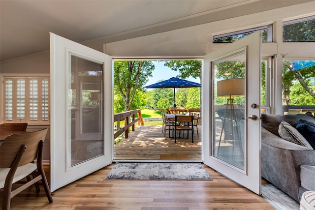 doorway with vaulted ceiling, light hardwood / wood-style flooring, and crown molding