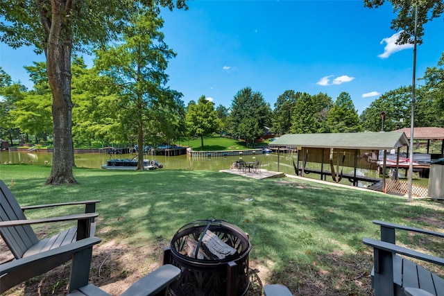 view of community featuring a fire pit, a dock, a water view, and a yard