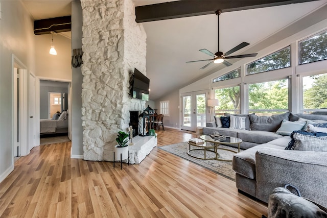 living room featuring light wood-type flooring, beam ceiling, and a fireplace