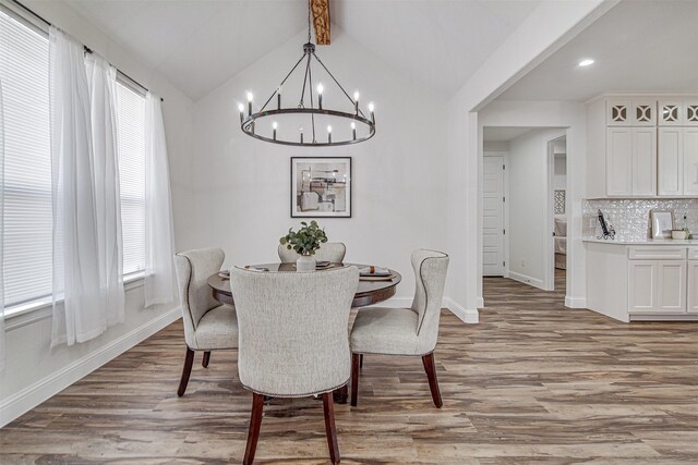 dining area with a chandelier, light wood-type flooring, and vaulted ceiling with beams