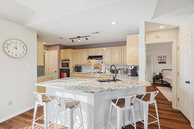 kitchen featuring sink, stainless steel microwave, backsplash, kitchen peninsula, and black oven