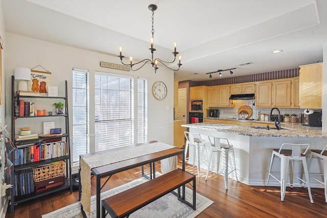 kitchen featuring sink, built in microwave, tasteful backsplash, black oven, and a chandelier