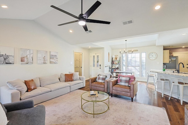 living room with lofted ceiling, ceiling fan with notable chandelier, dark wood-type flooring, and sink