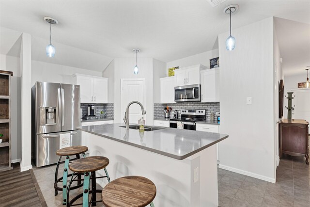 kitchen with decorative backsplash, sink, stainless steel appliances, and an island with sink