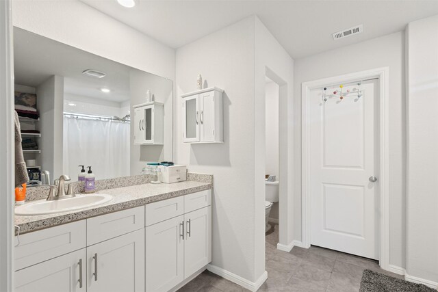 bathroom featuring tile patterned floors, vanity, toilet, and curtained shower